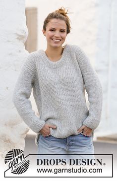 a woman standing in front of a white wall with her hands on her hips and smiling