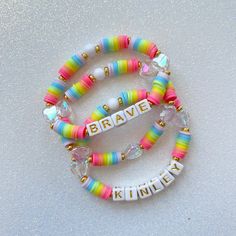 three bracelets that say brave and one with beads on them, sitting next to each other