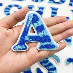 a hand holding a blue and white letter shaped sticker