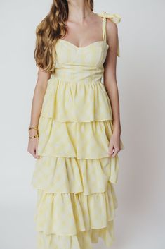 A stunning silhouette paired with summer-ready seersucker - the Jacquelyn Midi Dress has it all! This lovely gown is constructed from a textured, lightweight seersucker fabric in a playful plaid print, and features a sweetheart neckline, bustier bodice, and multi-tiered ruffle skirt. Pair with dainty heels for your next special event! FIT: Runs true to size. Bustier bodice is fitted, with a defined bust. MATERIAL: Hand wash cold, do not bleach. Line dry, do not tumble dry. Iron low if needed. GARMENT DETAILS: Plaid seersucker midi dress, with sweetheart neckline and bow-tie shoulder straps. Features a structured bustier-style bodice with defined bra, and a full skirt with multiple flounced tiers. SIZE GUIDE: S (2-4) / M (6-8) / L (10-12) MODEL DETAILS: Mackenzie - Size S Heather - Size S M Summer Dresses With Smocked Bodice For Picnic, Summer Plaid Dress With Ruffle Hem For Picnic, Gingham Dress With Smocked Back For Garden Party, Summer Plaid Dress With Smocked Bodice, Summer Gingham Tiered Dress, Gingham Tiered Dress For Picnic, Tiered Gingham Dresses For Summer, Summer Tiered Gingham Dress, Chic Smocked Bodice Dress For Picnic