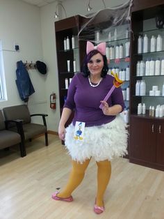 a woman in a costume holding a toothbrush and standing on a hard wood floor