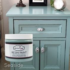 a blue dresser with a white clock on top and a jar of paint next to it