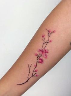 a woman's arm with pink flowers and leaves on the left side of her arm