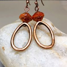 Hoop earrings in copper with stunning Saturn beads that are capped with a copper finish. These simple yet sophisticated dangle earrings are lightweight and comfortable for all day wear. Fabulous earrings in a trending color that can be worn with so many different outfits.   Hypoallergenic ear wires (nickel and lead free). Select ear wire style at checkout. Free gift packaging included. Earrings are carded and in an organza bag. Artisan glass beads produced in small quantities in the Czech Republ Elegant Copper Earrings With Dangling Beads, Brown Metal Hoop Earrings, Handmade Copper Beaded Earrings, Adjustable Copper Beaded Drop Earrings, Bronze Copper Hoop Earrings, Bronze Copper Beaded Dangle Earrings, Copper Teardrop Hoop Earrings With Ear Wire, Bronze Copper Dangle Beaded Earrings, Bronze Copper Earrings With Dangling Beads