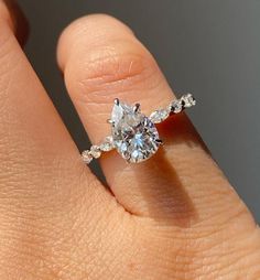 a woman's hand with a diamond ring on top of her finger and an engagement band