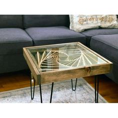 a glass table sitting on top of a wooden floor next to a gray couch in a living room