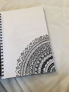 a spiral notebook with an intricate design on the front and back cover, sitting on top of a white sheet