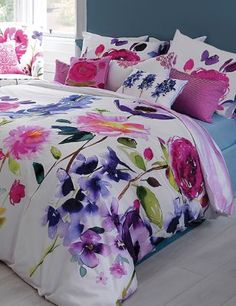 a bed with purple and pink flowers on it, in front of a window that reads wayfair co uk