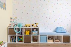 a child's room with toys and bookshelves on the floor, wallpapered in sprinkles