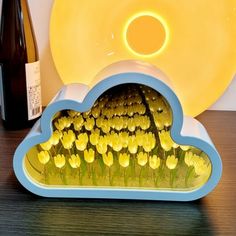 there is a vase with yellow flowers in it next to a wine bottle and plate