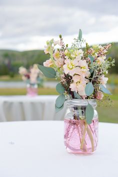 a vase filled with flowers sitting on top of a table next to a white table cloth