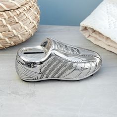 a pair of silver shoes sitting on top of a white table next to a basket