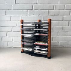 a wooden rack with cd's on it in front of a white brick wall