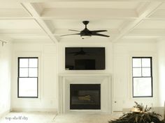 an empty living room with a fireplace and ceiling fan in the middle of the room