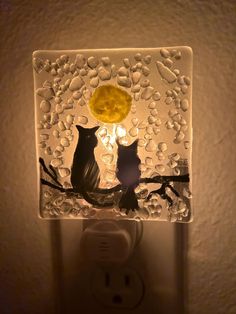 two cats sitting on a branch under a light switch cover with water droplets around it