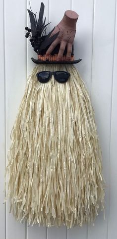 a wall hanging with a hat, sunglasses and fake grass skirt on it's head