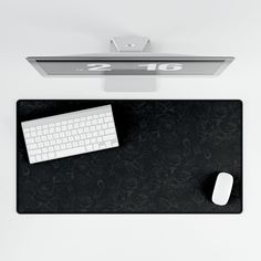 there is a keyboard and mouse on the black desk mat next to the computer monitor