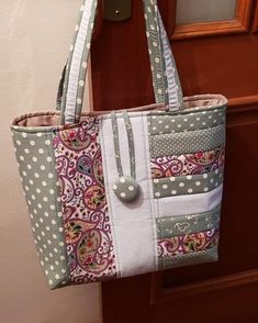 a handbag hanging on a door with polka dots and paisley print, in front of a mirror