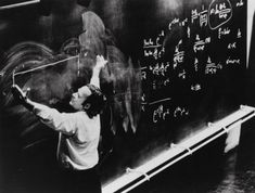 a man writing on a blackboard with chalk