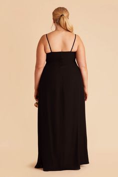 a woman in a black dress is looking back at the camera and has her hands on her hips