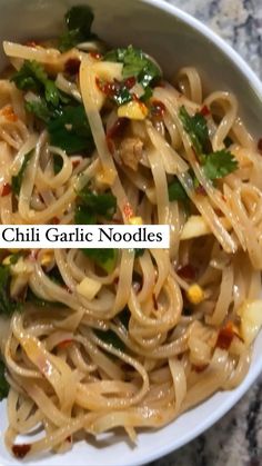 a white bowl filled with noodles and vegetables on top of a marble countertop next to the words chilli garlic noodles