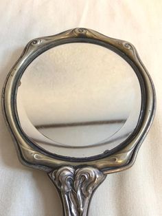 a mirror that is sitting on top of a white cloth covered tablecloth, with the reflection of an ornate design in it