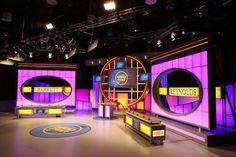 three television sets with purple and yellow lighting in the middle of an empty studio area