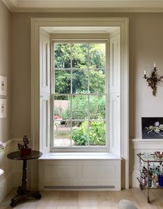 an empty room with a large window in the center and small table on the other side