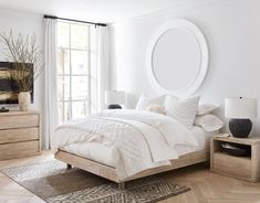 a bedroom with a bed, nightstands and large round mirror on the wall above it