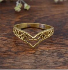 a gold ring sitting on top of a wooden table next to some flowers and leaves