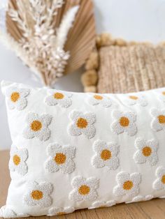 a white pillow with yellow polka dots on it sitting next to a dried flower arrangement