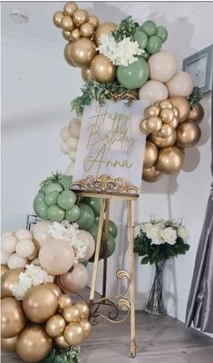 a happy birthday sign surrounded by balloons and flowers