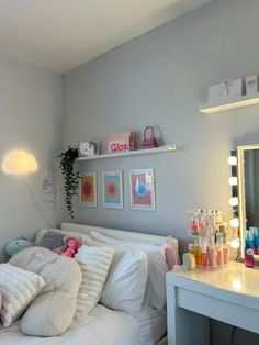 a white bed sitting in a bedroom next to a mirror and desk with lights on it