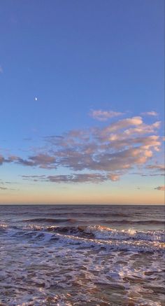 an ocean view with waves crashing on the shore and a full moon in the sky