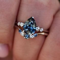 a woman's hand holding a blue and white diamond ring