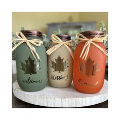 three mason jars with maple leaves painted on them, tied in twine and sitting on a table