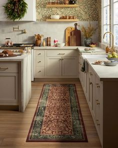 a kitchen with white cabinets and wooden floors has a rug on the floor in front of the sink