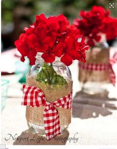 a cell phone with an image of red flowers in a mason jar on the screen