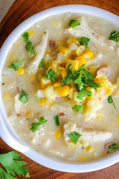 a white bowl filled with chicken and corn chowee on top of a wooden table