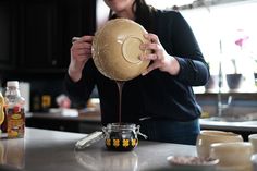 a woman is pouring something into a jar