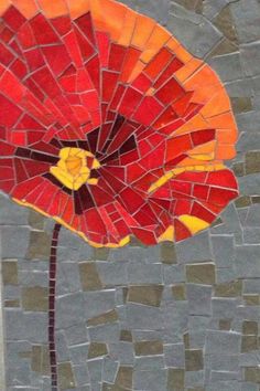 a red flower is made out of broken glass mosaics and has yellow petals in the center