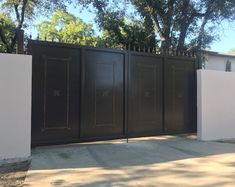 a gated in area next to a house with trees and bushes on the other side