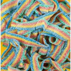 rainbow colored streamers are piled on top of each other in a pile with yellow background