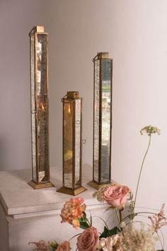 three candles are sitting on a table with flowers