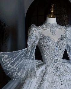 the back of a white ball gown with sheer sleeves and beadings on it