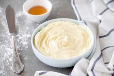 a bowl filled with cream next to two spoons