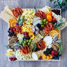 a platter filled with cheese, fruit and crackers