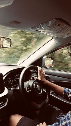 a man driving a car with his hands on the steering wheel while another person is sitting in the passenger seat