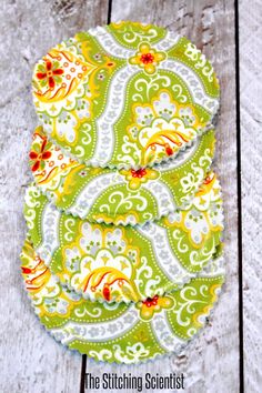 two green and yellow coasters sitting on top of a wooden table