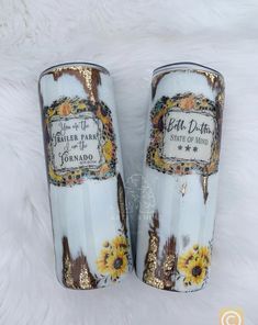 two white vases with sunflowers painted on them sitting next to each other